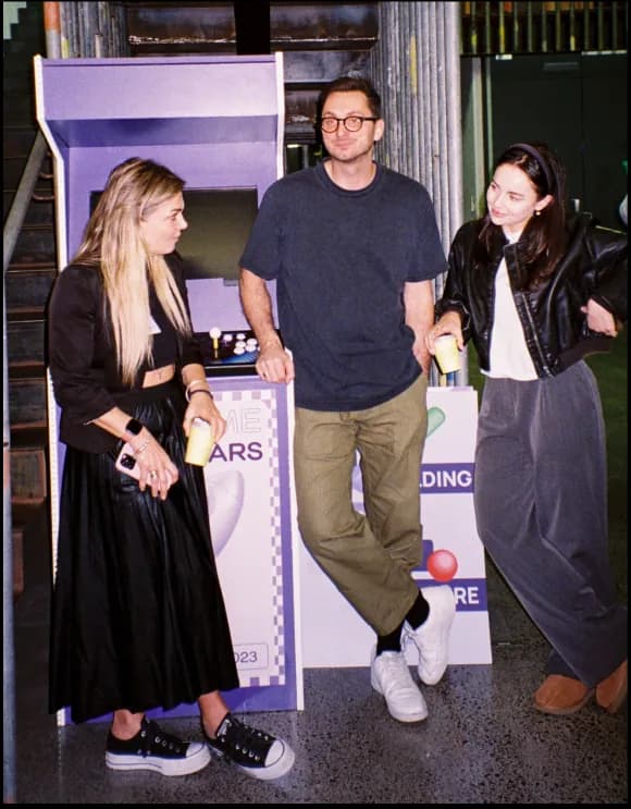 Three people gathered around an arcade machine
