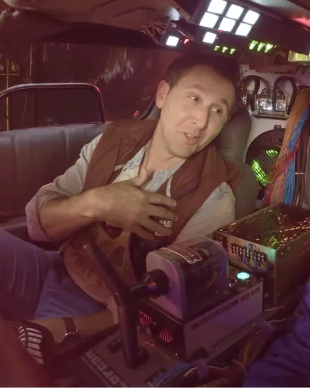 A man in a puffer vest sitting in a DeLorean time machine