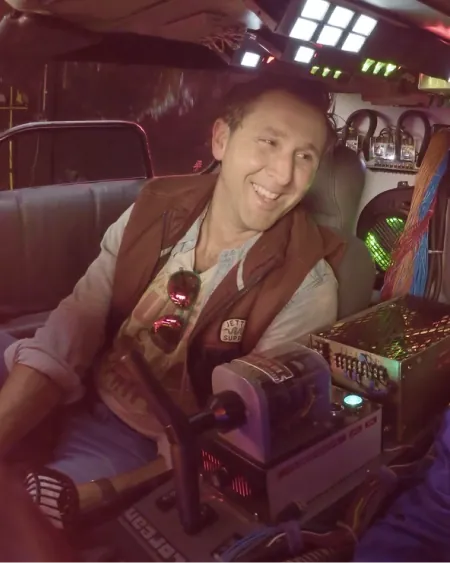 A man smiling in the driver's seat of a DeLorean time machine
