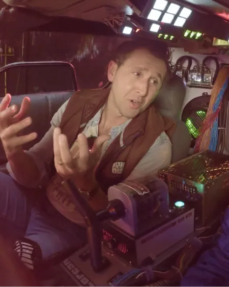 A man gesturing while seated in a DeLorean time machine